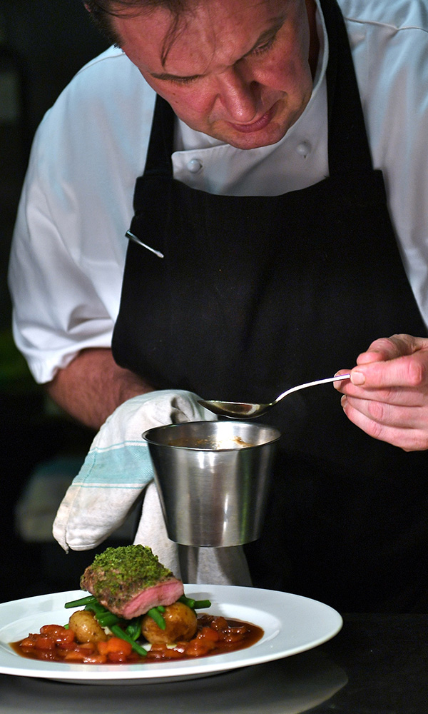 A chef serving food in the Columba Restaurant aboard the Hebridean Princess boat from Hebridean Island Cruises