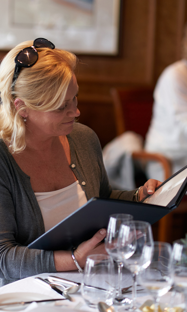Guest browsing the menu in Columba Restaurant on Hebridean Princess cruise ship