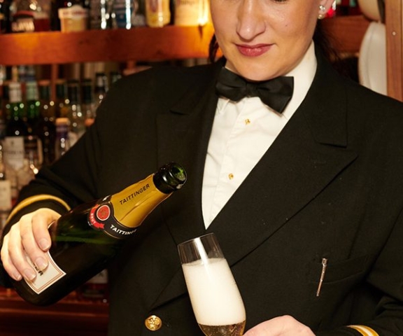 A crew member on Hebridean Princess cruise ship pouring a drink in the Tiree Lounge