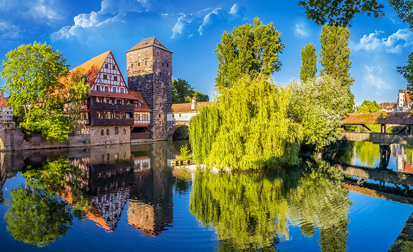 The beautiful historic buildings of the old town of Nuremberg and trees lining the river