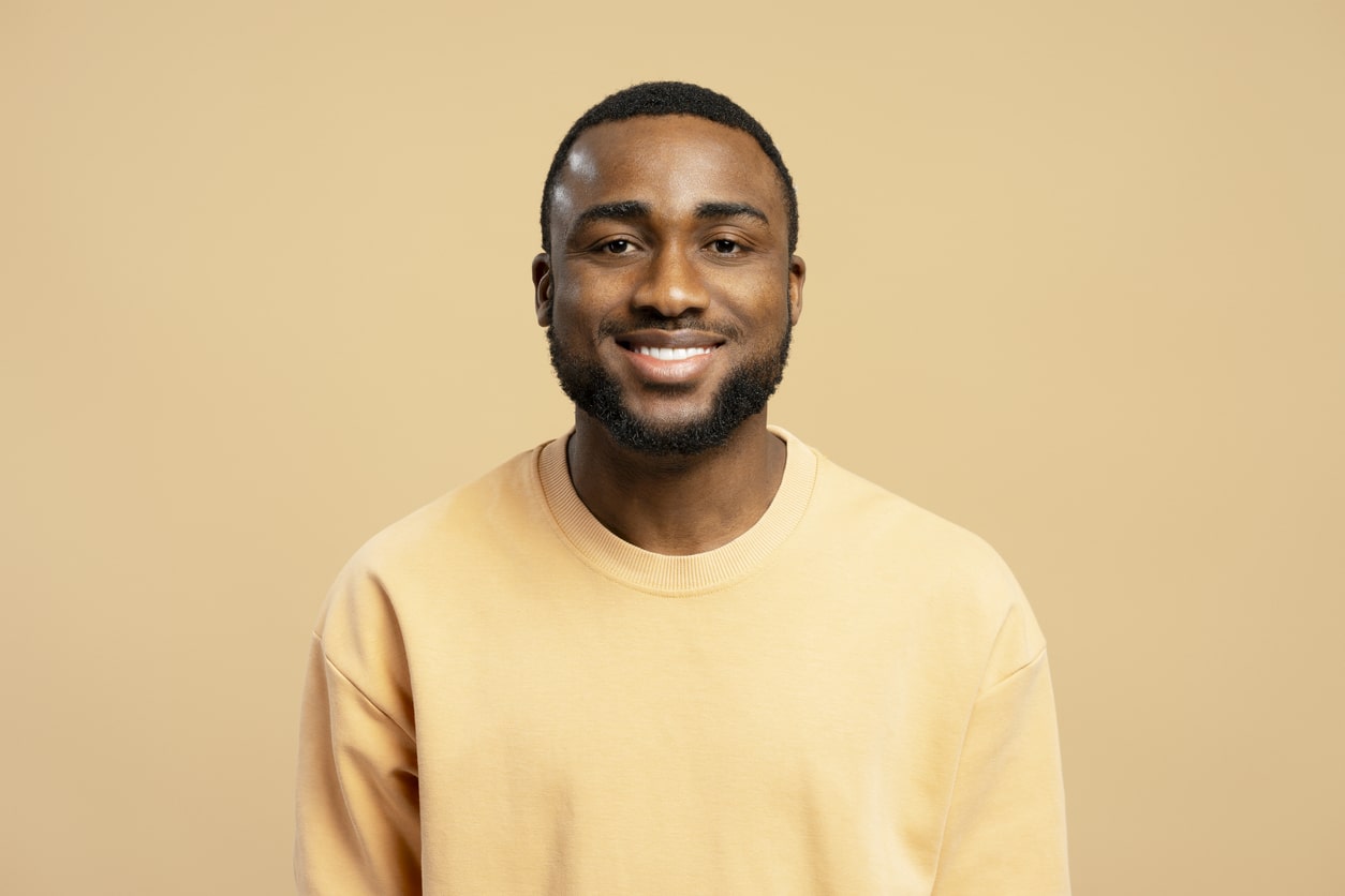 Studio portrait of happy african american man wearing beige sweatshirt smiling on beige background